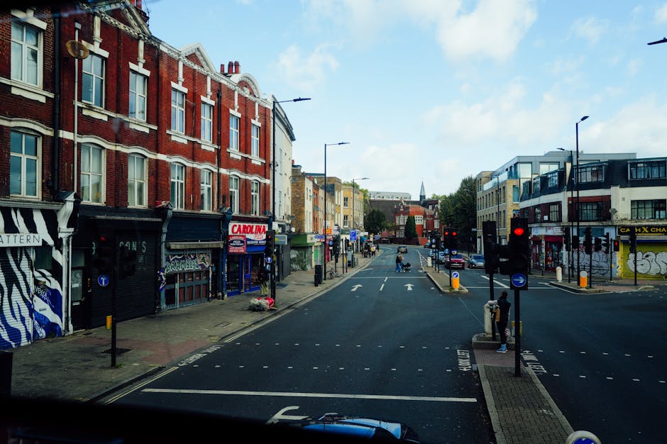 A quiet residential street on Rectory Road in Stoke Newington, showing Victorian-style terraced houses with white and dark-colored facades, brick and stucco finishes, and bay windows. The road is pave
